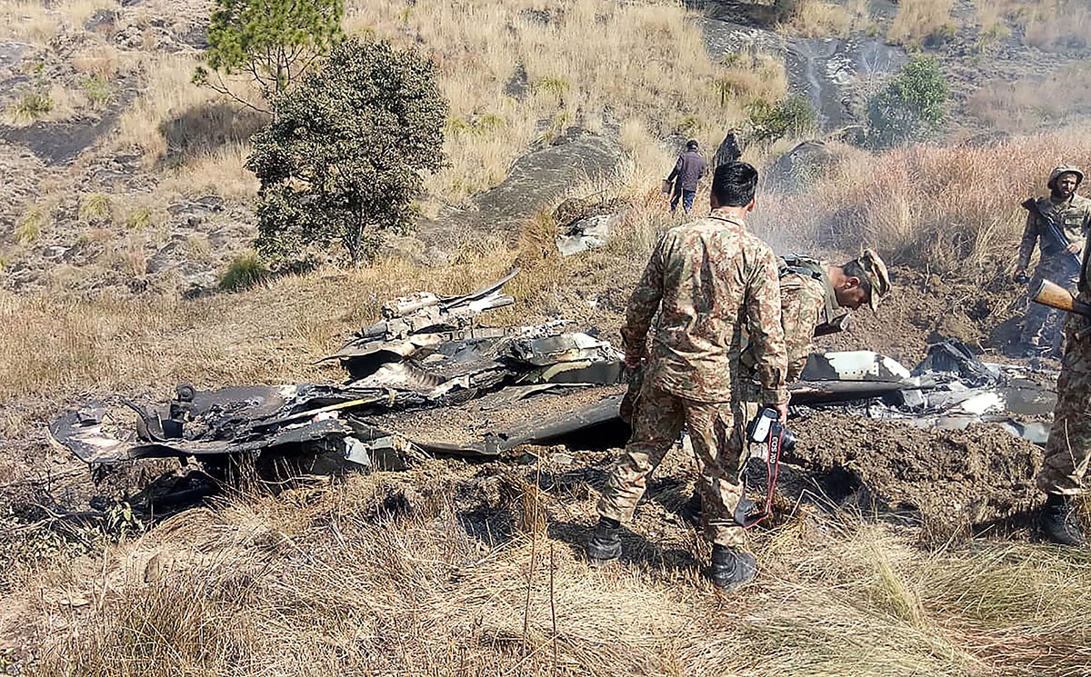 Pakistani soldiers stand next to what Pakistan says is the wreckage of an Indian fighter jet shot down in Pakistan controled Kashmir at Somani area in Bhimbar district near the Line of Control on February 27, 2019.