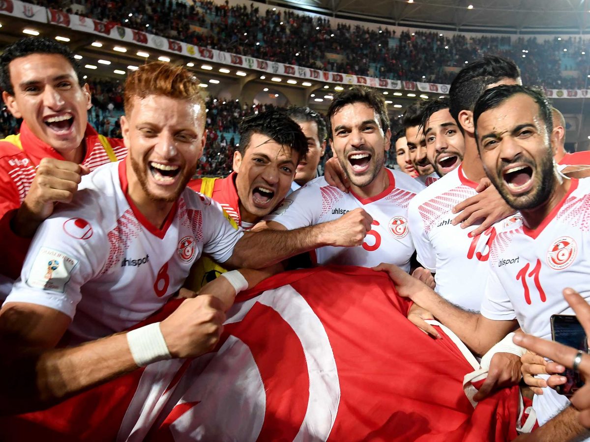 Tunisian national football team celebrate with their national flag after qualifying for the 2018 World Cup finals after drawing their qualifiers match against Libya at the Rades Olympic Stadium in the capital Tunis on November 11, 2017.