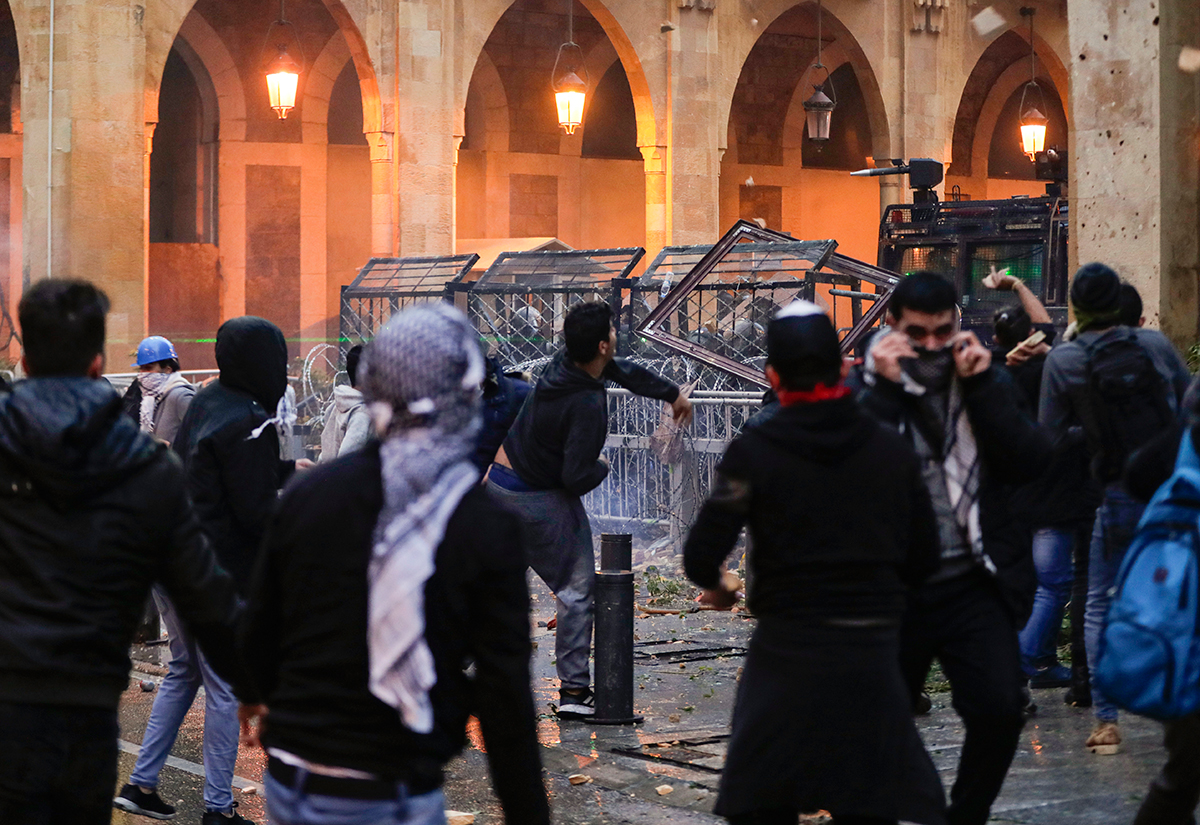 Anti-government protesters attempt to break through the security barrier in the central downtown district of the Lebanese capital Beirut near the parliament headquarters during clashes with security forces on January 18, 2020. Image: AFP