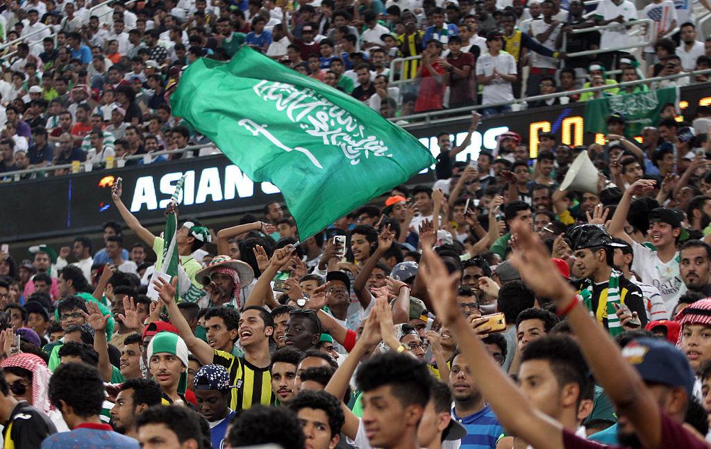 Saudi fans wave the national flag and chant during a 2018 World Cup qualifying football match. (AFP/Getty Images)