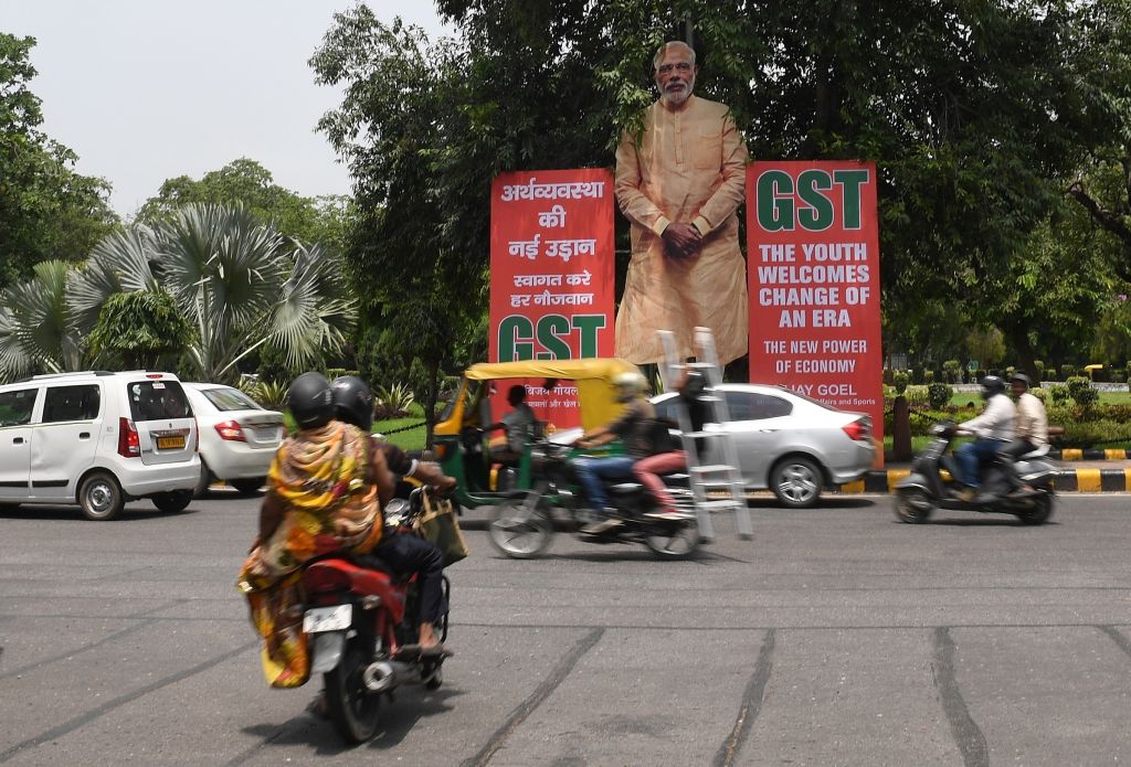 Indian motorists drive past a billboard displaying an image of Prime Minister Narendra Modi and announcing the implementation of the Goods Service Tax in New Delhi.
Photo credit should read PRAKASH SINGH/AFP/Getty Images