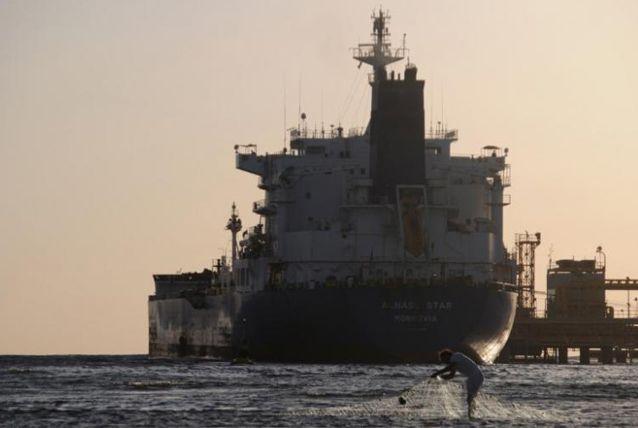 A fisherman pulls in his net as an oil tanker is seen at the port in the northwestern city of Duba April 20, 2013. Picture taken April 20. (REUTERS/Mohamed Al Hwaity)