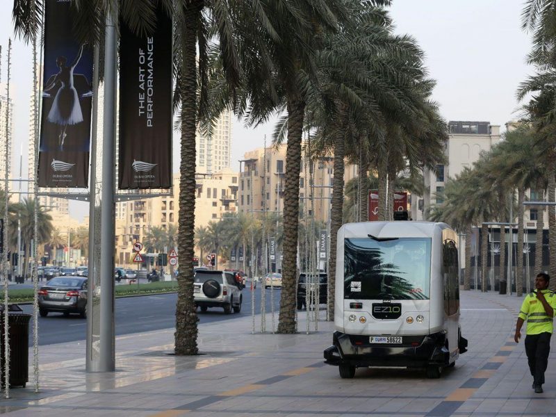 A man walks near an autonomous 10-seater car during a trial run along the Mohammed bin Rashid Boulevard on September 1, 2016. Dubais Roads and Transport Authority (RTA), in collaboration with the UAE real estate development company Emaar Properties, accomplished the first phase of an experiment to test driverless transit technology in the