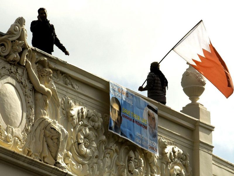 A man waves a Bahraini national flag from the top of the Bahraini Embassy in central London on April 16, 2012 during a protest over the imprisonment of political activist Abdulhadi al-Khawaja. (AFP/Getty Images)