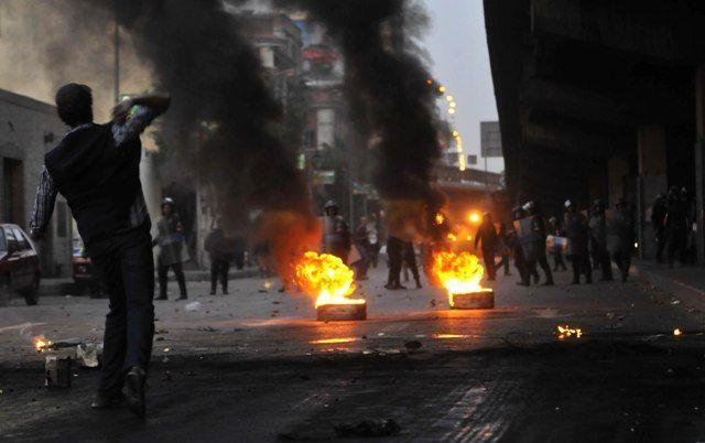 Egyptian riot police gather near burning tires as a demonstrator throws an object towards them during a protest on Wednesday in Cairo demanding the ouster of President Hosni Mubarak and calling for reforms (Getty Images)