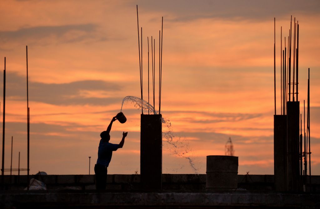 An Indian labourer pours water on a concrete pillar at a construction site as the sun sets in Bangalore on October 8 2018
Photo: MANJUNATH KIRANAFPGetty Images