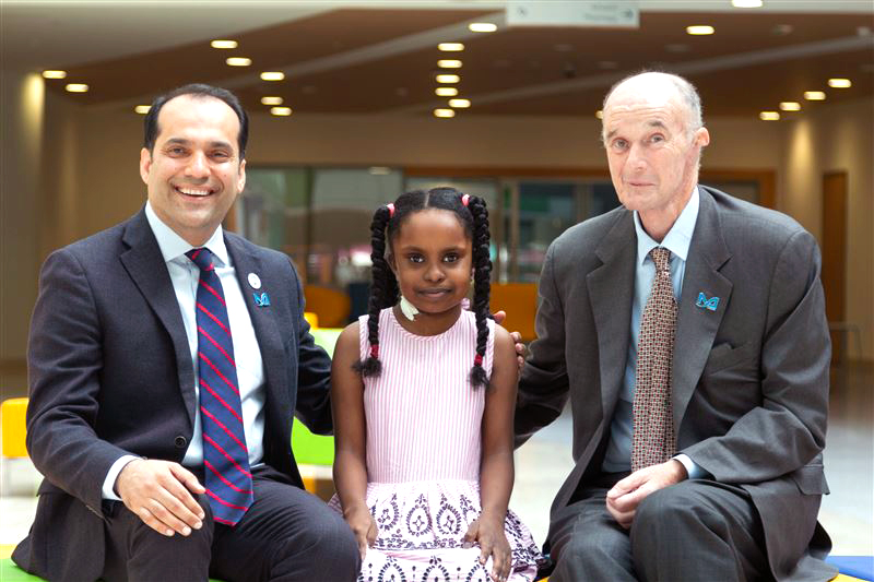 Dr Farhad Janahi, Assistant Professor of Surgery and Dr David Hickey, Professor of Surgery pictured with nine-year-old Bana Nizar Hassan.