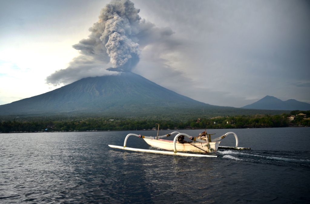 A fisherman drives a traditional boat as Mount Agung erupts seen from Kubu subdistrict in Karangasem Regency on Indonesias resort island of Bali. (SONNY TUMBELAKA/AFP/Getty Images)