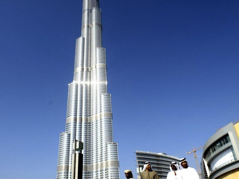 Emirati men walk by the Burj Khalifa, UAE nationals