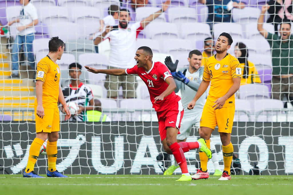 Salem AlAjalin of Jordan celebrates past dejected Massimo Luongo R and Mark Milligan of Australia after Anas Bani Yaseen of Jordan not in picture scored his team's goal during the AFC Asian Cup Group B match between Australia and Jordan at Hazza Bin Zayed Stadium