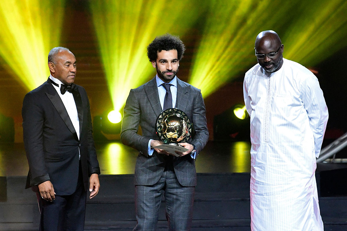 Confederation of African Football (CAF) President Ahmad Ahmad (L) poses after he handovered the 2018 African Footballer of the Year Award also called Ballon d'Or to Liverpool's Egyptian forward Mohamed Salah (C) past Liberian President George Weah during an award ceremony in dakar on January 8, 2019.