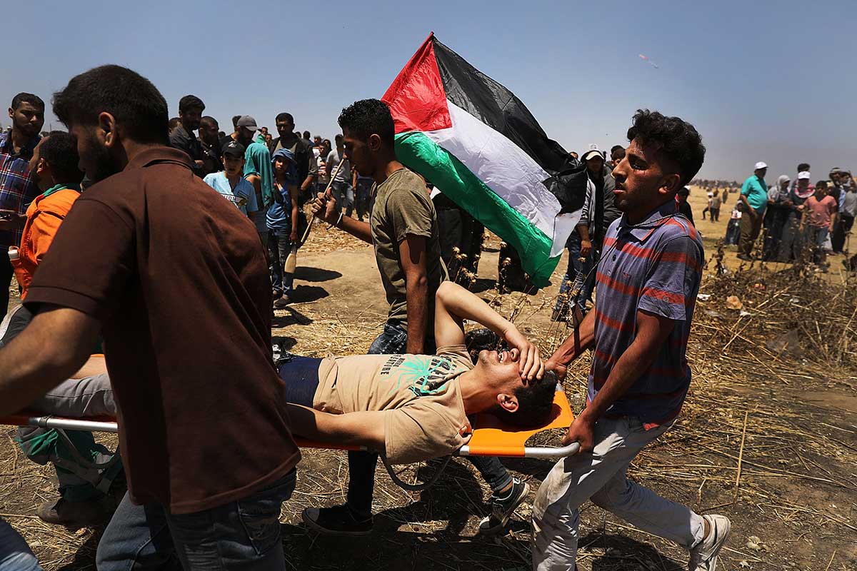 A wounded Palestinian man is rushed to an ambulance at the border fence with Israel as mass demonstrations continue on May 14, 2018 in Gaza.