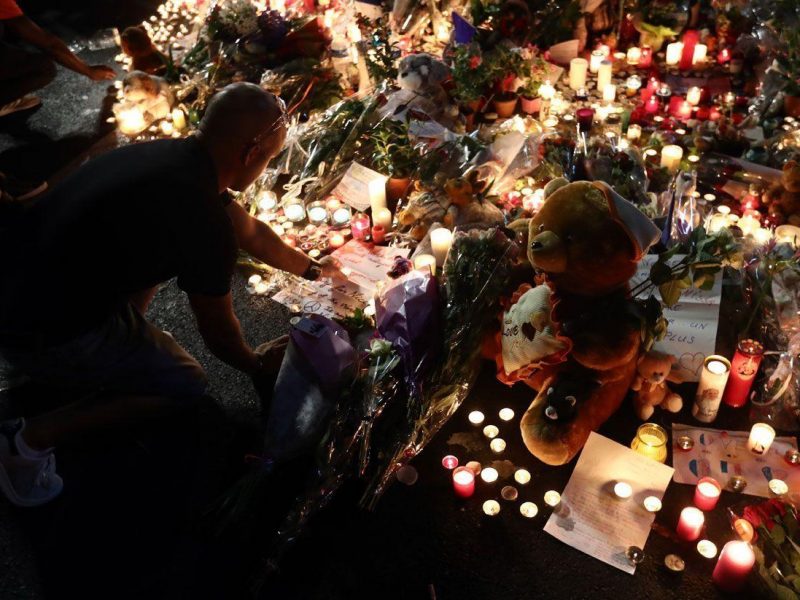 A man places a candle among flowers and tributes on the Promenade des Anglais on July 16, 2016 in Nice, France. (Getty Images)