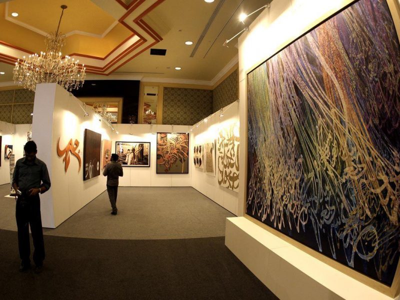 Visitors stand next to artwork to be auctioned off by Sothebys at Arts of the Islamic World in a preview exhibition in Doha