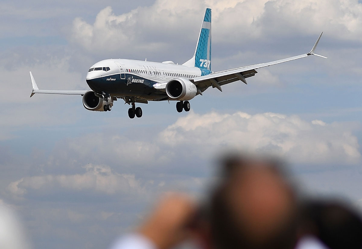 Visitors watch as a Boeing 737 Max lands after an air display during the Farnborough Airshow, south west of London, on July 16, 2018.