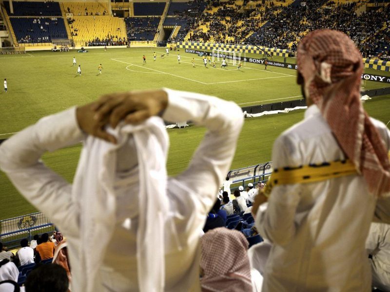 Fans wearing traditional local dress react to play during the Gharafa vs. Kharaitiyat Qatar Stars League football match at Al Gharafa Stadium on October 23, 2011 in Doha, Qatar. Qatar will host the 2022 FIFA World Cup football competition and is slated to tackle a variety of infrastructure projects, including the construction of new stadiu