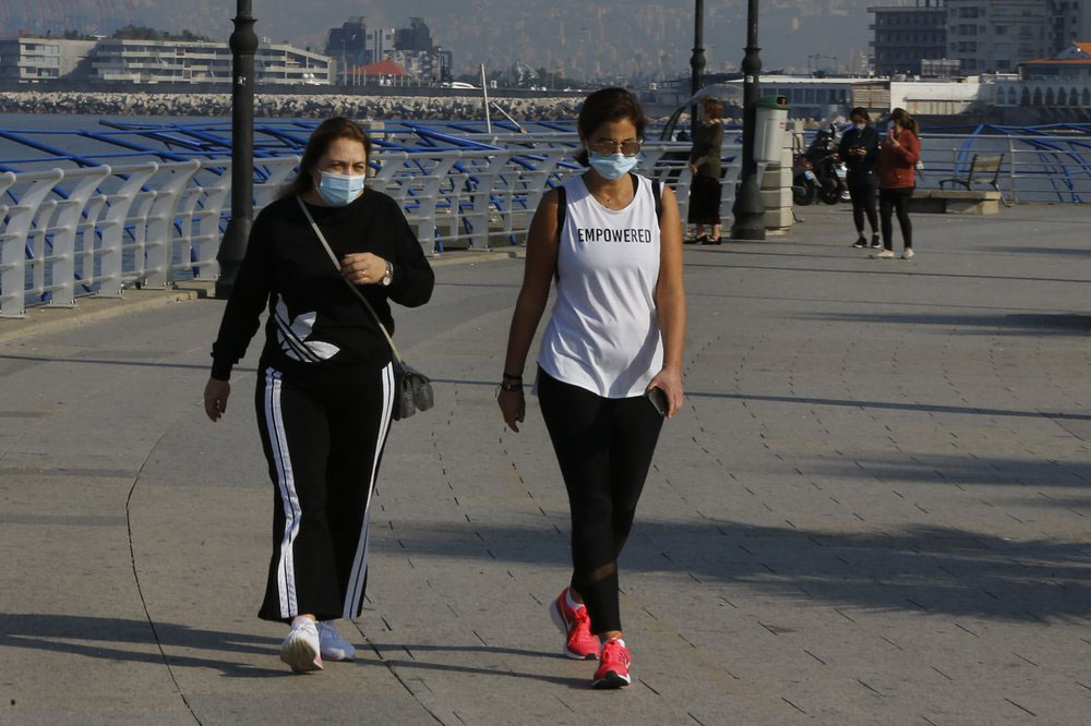 Two women wearing face masks exercise on Beirut's Mediterranean seaside corniche.