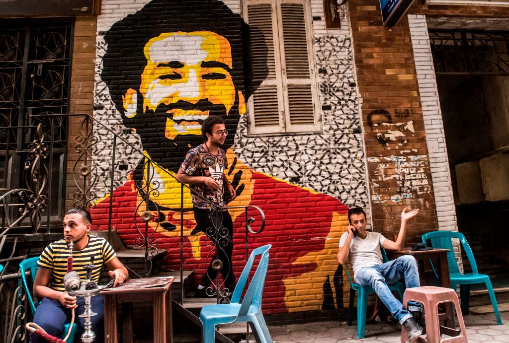 Ahmed Fathy (centre) a 26-year-old Egyptian artist descends a small staircase at an openair cafe in downtown Cairo, past a mural he painted depicting the smiling face of Liverpool's Egyptian midfielder Mohamed Salah.Photo: KHALED DESOUKI/AFP/Getty Images.