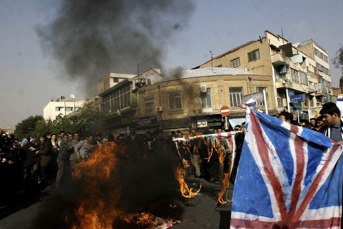 A group of Iranian hardliners burn a British flag during a protest outside the British embassy in Tehran