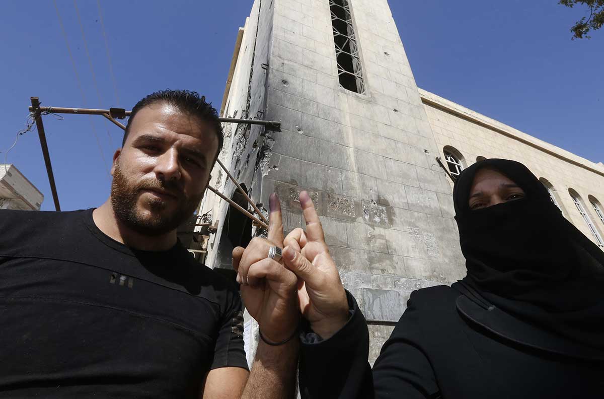 A man and a woman show their ink-stained index fingers after voting for Syria's first local elections since 2011, on September 16, 2018 in the southern Eastern Ghouta, on the eastern outskirts of the capital Damascus.