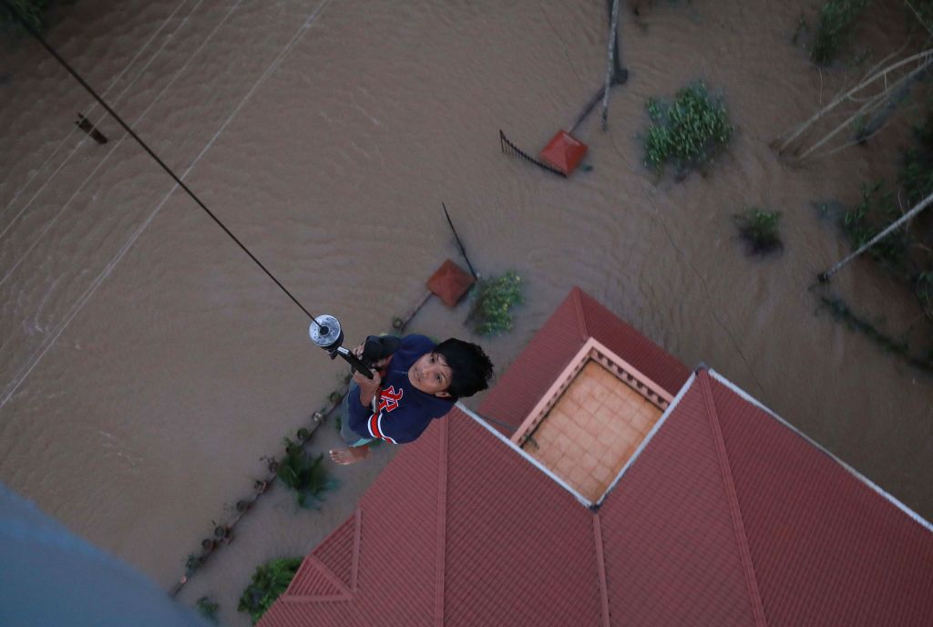 Indian people are airlifted by Navy personnel during a rescue operation at a flooded area in Paravoor near Kochi in the Indian state of Kerala. Rescuers in helicopters and boats fought through renewed torrential rain on August 18 to reach stranded villages in Indias Kerala state as the toll from the worst monsoon floods in a century rose a