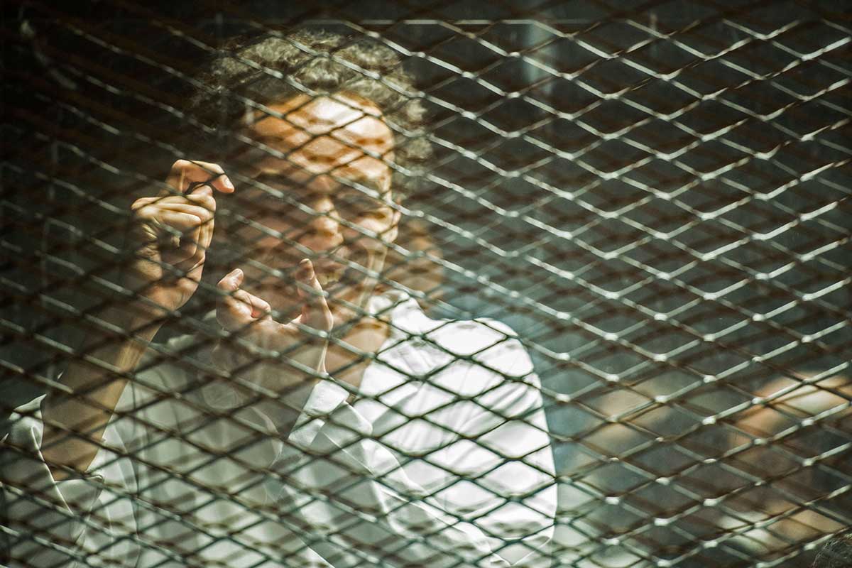 Egyptian photojournalist Mahmoud Abu Zeid, widely known as Shawkan, mimes a photographer inside a soundproof glass dock during his trial in the capital Cairo, on September 8, 2018.