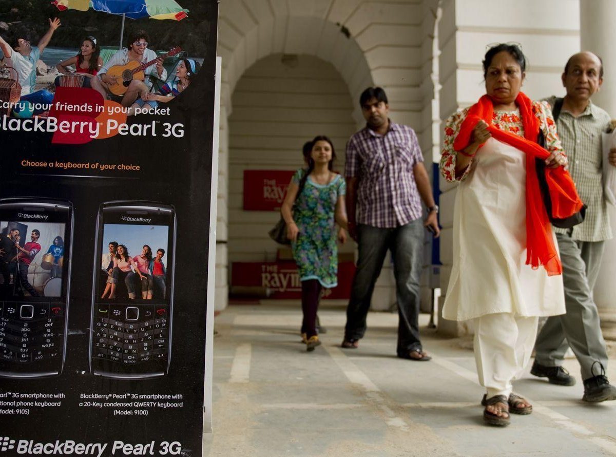 Pedestrians walk past a BlackBerry billboard placed outside a shop in New Delhi