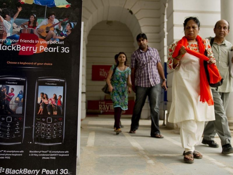 Pedestrians walk past a BlackBerry billboard placed outside a shop in New Delhi