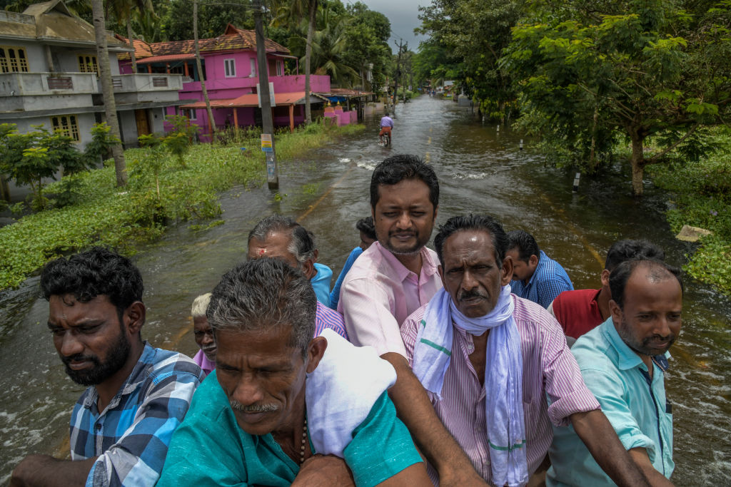 Locals cross the flood water after taking the lift on the rescue truck in Chengannur, India.  (Atul Loke/Getty Images)