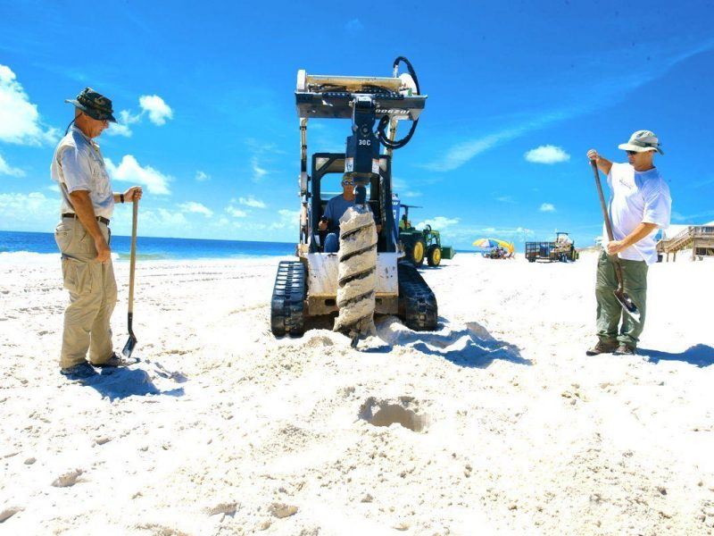 Beach clean-up teams on the Gulf of Mexico coastline. Sand core analysis tests for oil presence beneath the surface.