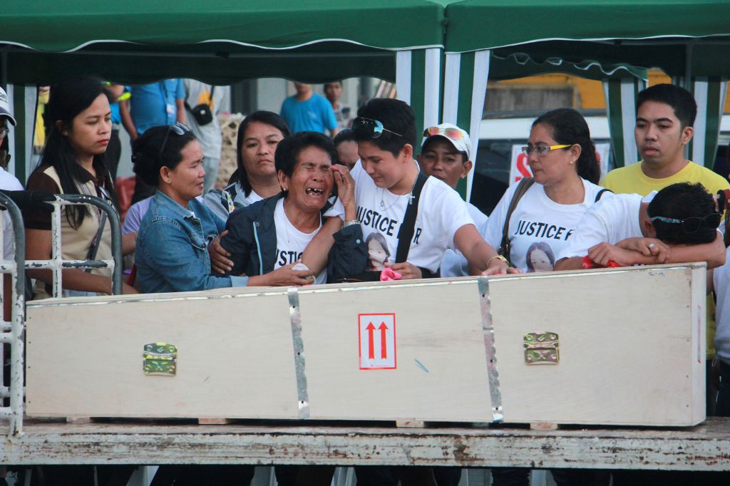 Eva 3rd L mother of Filipina worker Joanna Demafelis whose body was found inside a freezer in Kuwait cries in front of the wooden casket containing her daughters body shortly after its arrival from Manila at Iloilo International Airport in Iloilo province central Philippines on February 17 2018. The body of Filipina worker Joanna Demafelis