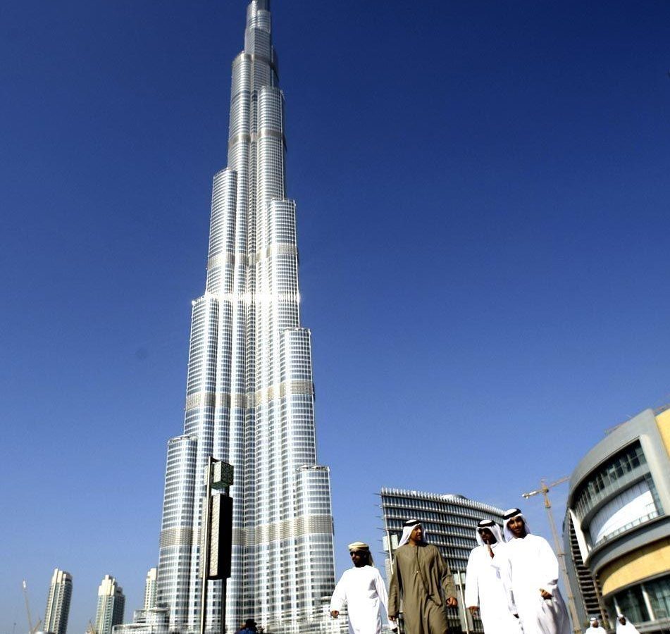 Emirati men walk by the Burj Khalifa, UAE nationals