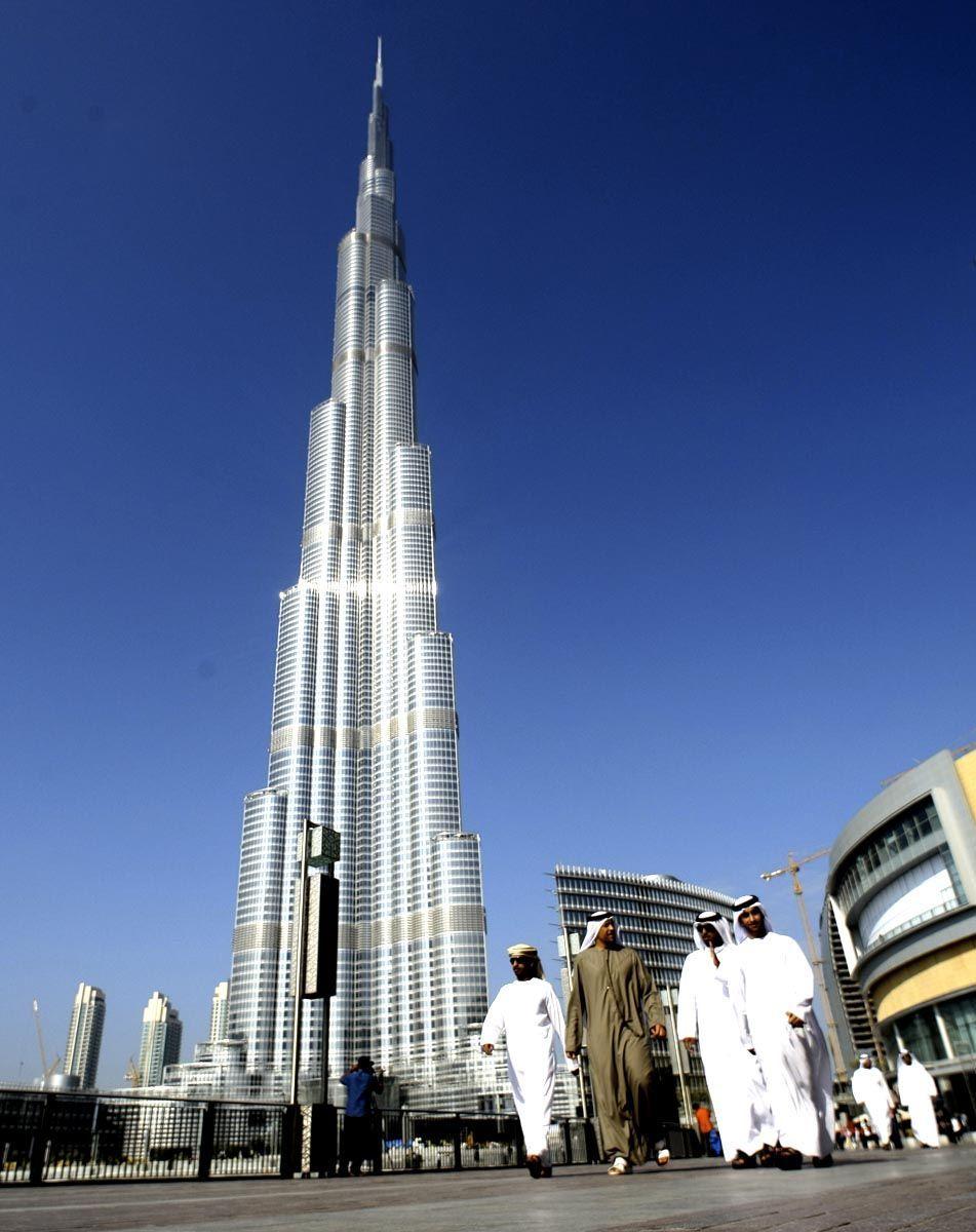 Emirati men walk by the Burj Khalifa, UAE nationals