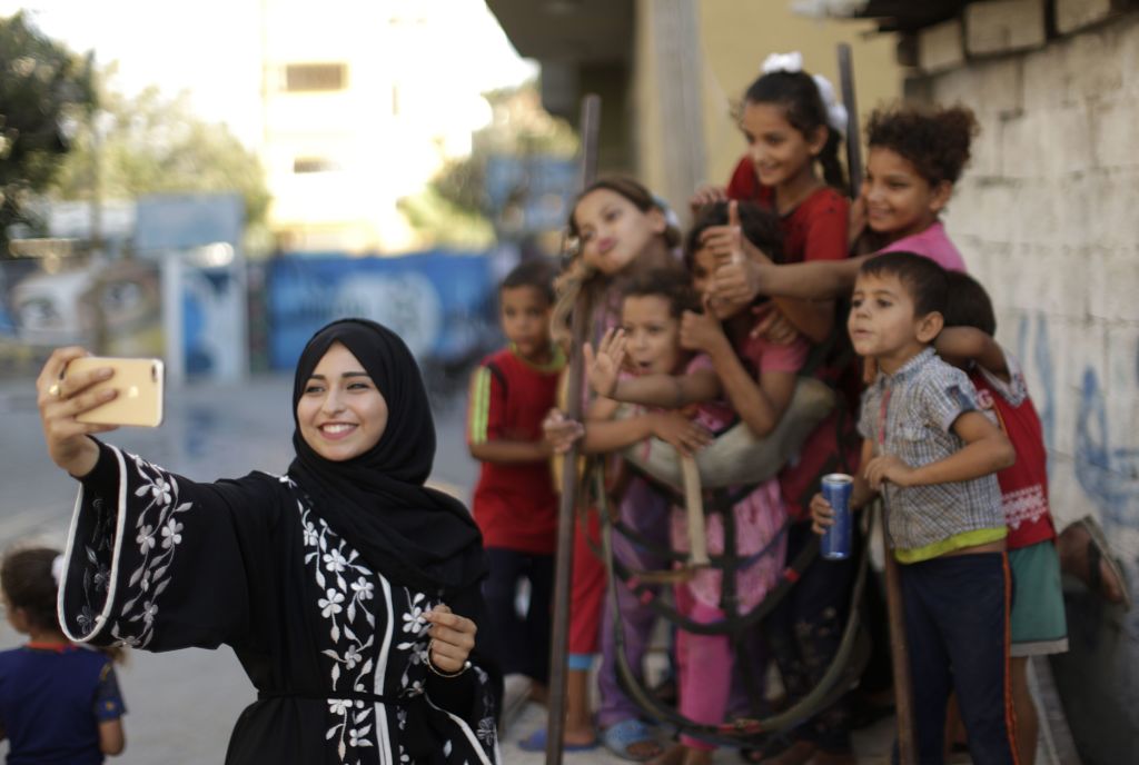 Palestinian Fatma Abu Musabbeh uses her mobile phone to take pictures of children for her social media account in Deir alBalah in the central Gaza strip. 
Photo: MAHMUD HAMS/AFP/Getty Images