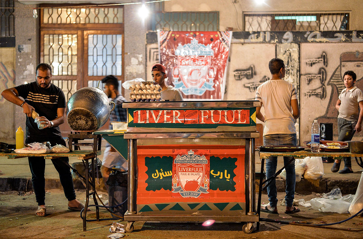 Egyptians cook food during the pre-dawn 'suhur' meal before a new day of fasting begins, early on May 31, 2019, near a food cart by the name "Liver Fuul", a play on Arabic name for fava beans and English football club Liverpool FC, in the Ain Shams suburb of northeastern Cairo.