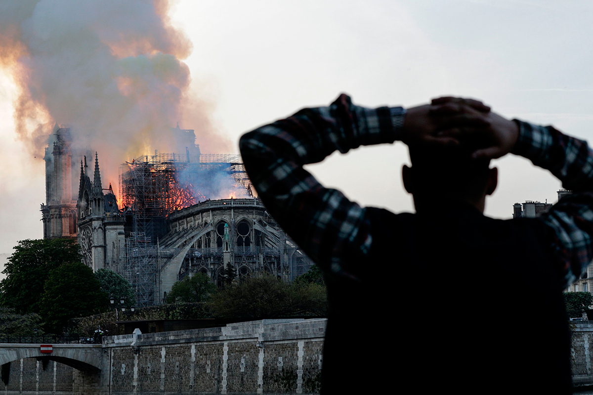 A man watches the landmark Notre-Dame Cathedral burn, engulfed in flames, in central Paris on April 15, 2019.
(Photo: GEOFFROY VAN DER HASSELT/AFP/Getty Images).