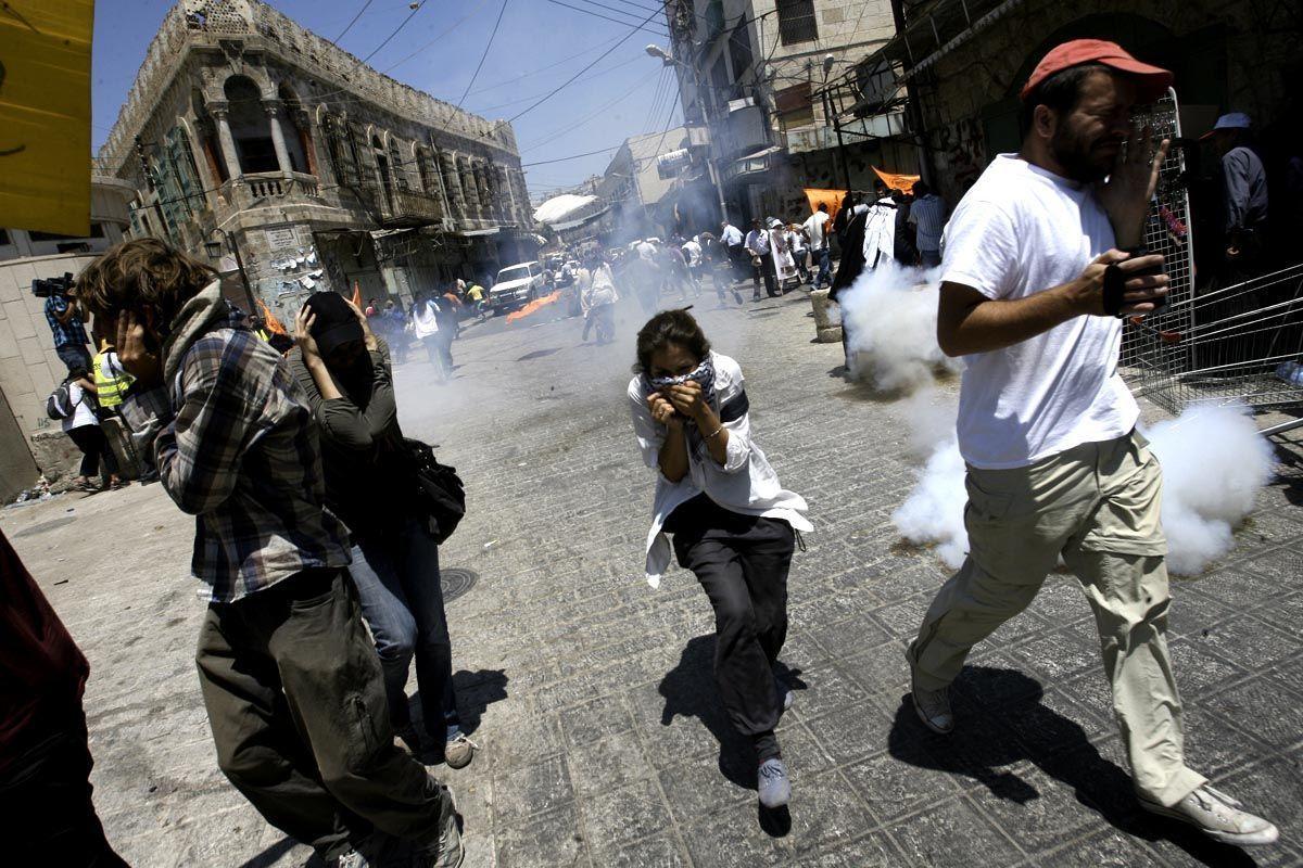 Palestinian and foreign demonstrators run from tear gas smoke fired by Israeli troops in the occupied West Bank